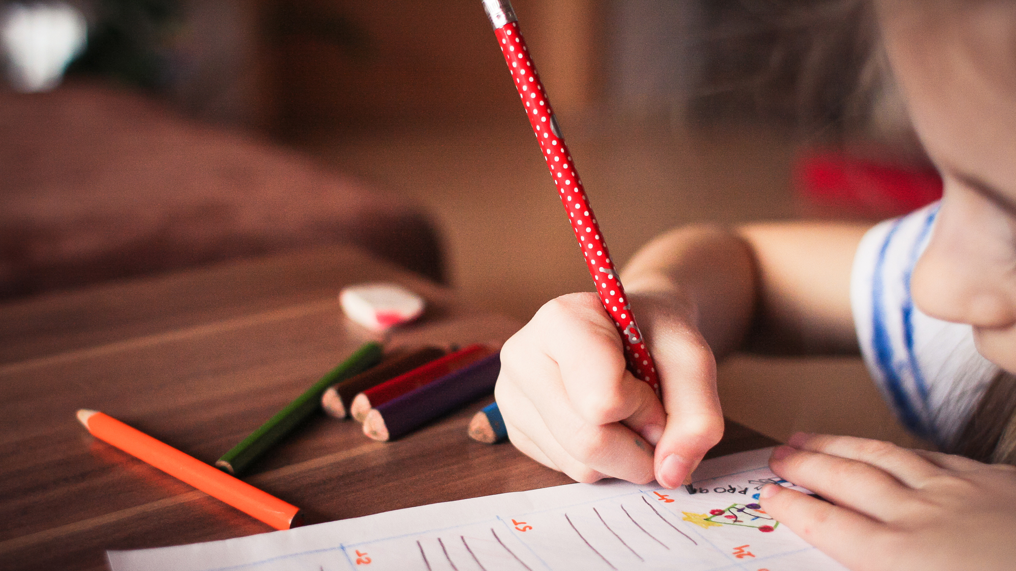 Kind füllt mit Bleistift einen Bogen aus.