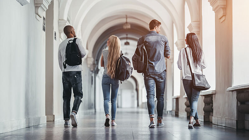 Studierende oder Auszubildende, die den Flur eines Gebäudes bspw. einer Universität herunterlaufen