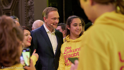 Christian Lindner beim Dreikönigstreffen der Freien Demokraten 2023 mit jungen Menschen, die einen Pullover tragen, auf dem steht "Die Zukunft glaubt an uns."