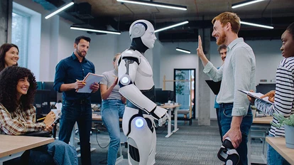 Ein Mann steht vor einem Roboter in einem Büro.