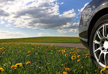 Klima: Auto auf einer Straße an Wiese mit Blumen