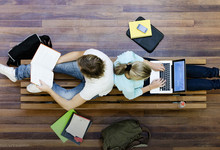 Studenten sitzen auf dem Boden mit Laptops