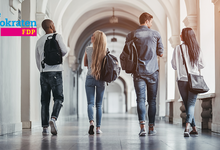 Studentinnen und Studenten laufen einen Flur einer Universität entlang.