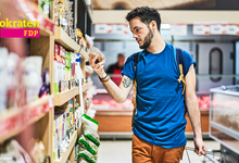 Inflation: Junger Mann im Supermarkt beim Einkaufen vor einem Regal