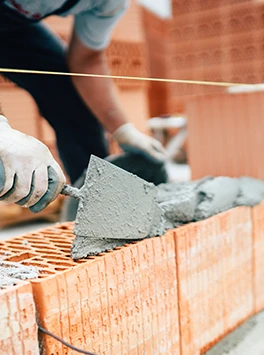 Mittelstand: Maurer setzt Steine aufeinander auf Baustelle