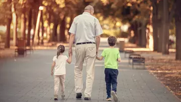 Rente: Großvater läuft mit seinen zwei Enkelkindern an der Hand