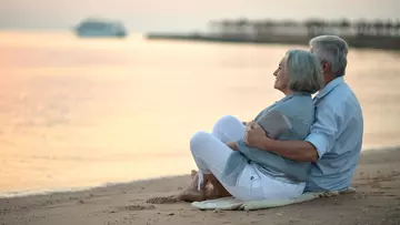 Rente: Senioren Paar sitzt am Strand, Sonnenuntergang