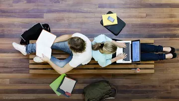 Studenten sitzen auf dem Boden mit Laptops