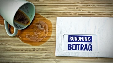 Kaffeebecher und Brief Rundfunkbeitrag